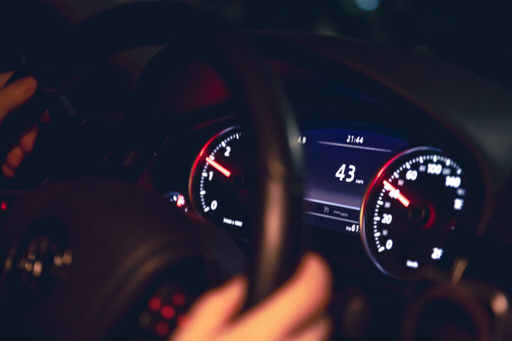 Speed indication and women's hands on the steering wheel in a car at night.